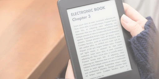 Person wearing a dark sweater, showing their hand holding an e-book reader